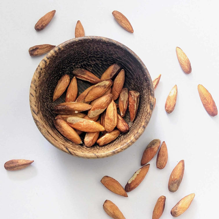 Dried almond seeds in a wooden bowl, healthy edible nuts for snacking and cooking.