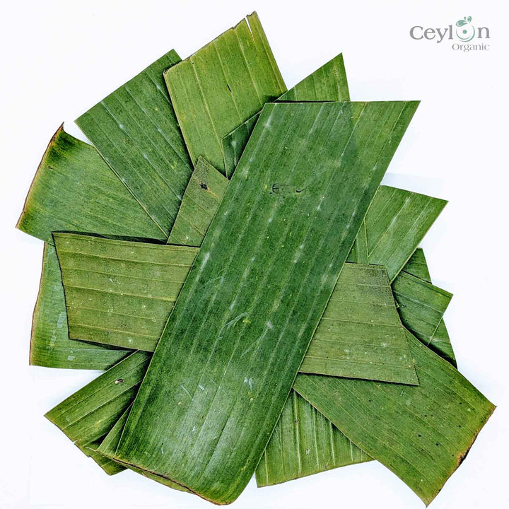 Banana leaves used as a basket-weaving material,Close-up of a banana leaf with water droplets,A banana leaf being used to wrap a Thai dish,A banana leaf being used to decorate a table setting,A banana leaf roof on a traditional Balinese house.