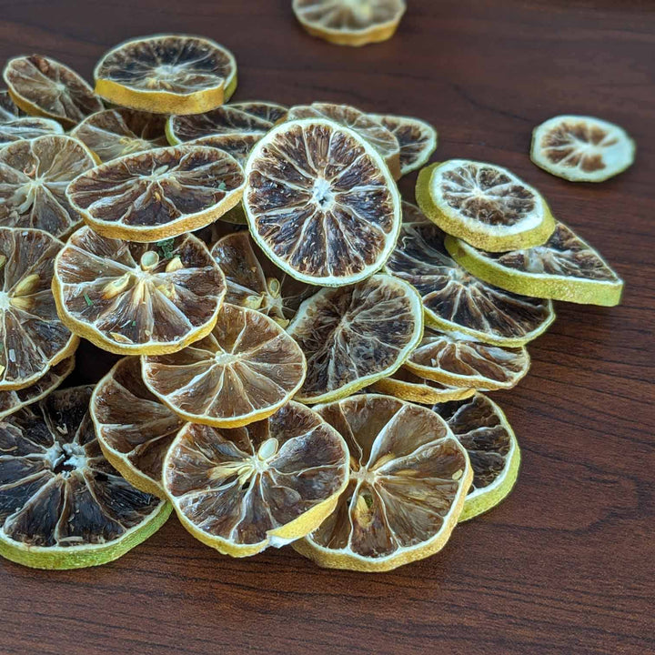 ,Dried lemon slices on a wooden surface,Dried Lime Chips: Zesty, Crunchy & Naturally Sweet.