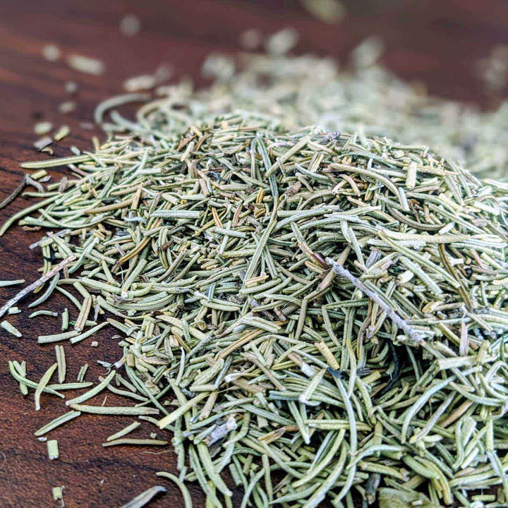 Dried green herbs on a wooden surface,dried rosemary spice sprinkled over roasted potatoes and chicken

