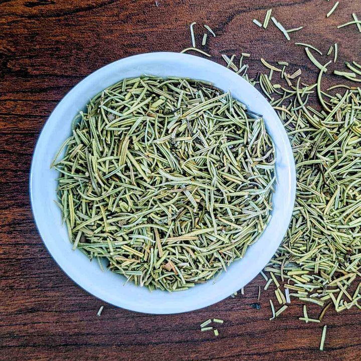 Dry herb strands in a white bowl on a wooden surface
